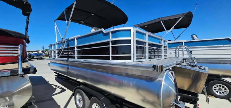 Slide: The Image of 2025 South Bay 224FCRLE pontoon boat with black canopy on trailer. - 1