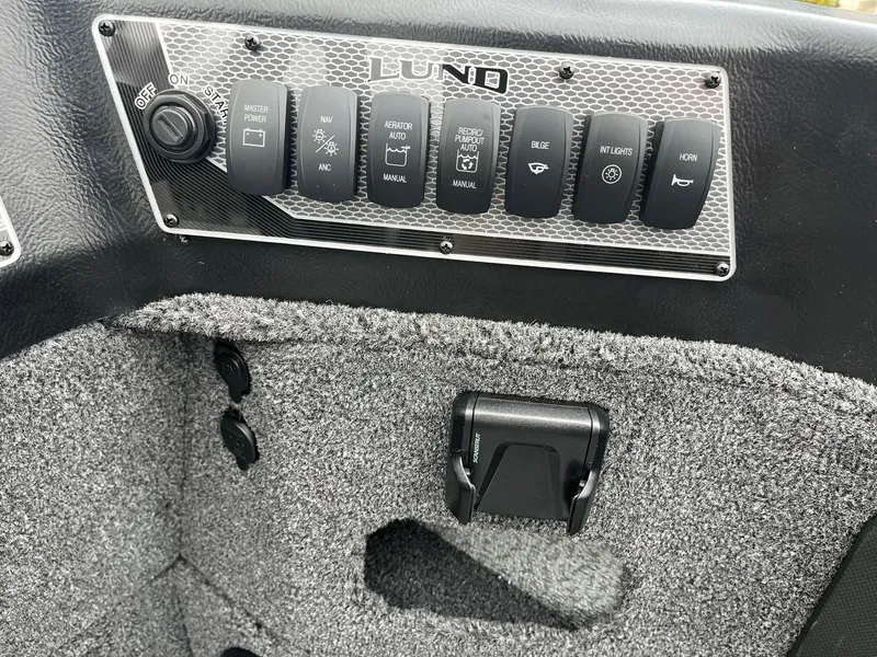 Slide: The Image of Control panel of 2025 Lund 1875 Impact XS SS boat with switches and textured interior. - 19