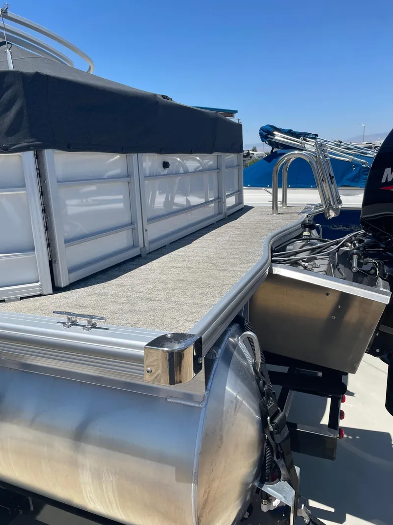 Slide: The Image of 2025 South Bay 224FCRLE pontoon boat with covered deck and motor, docked under clear sky. - 19