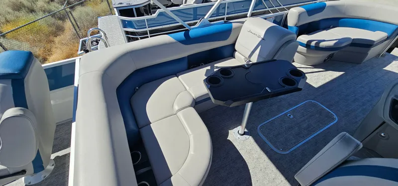 Slide: The Image of 2025 South Bay 224FCRLE pontoon boat interior with gray and blue seating and a central table. - 4