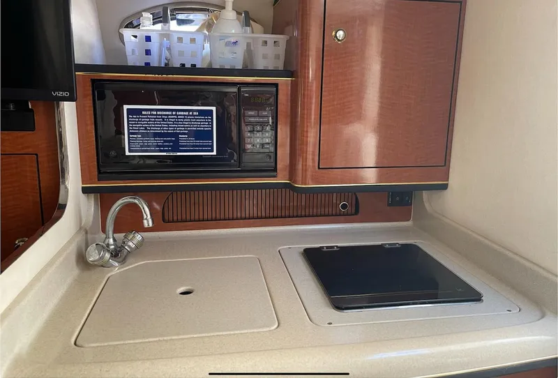 Slide: The Image of 2002 Sea Ray 280 Sundancer galley with sink, stove, and microwave. - 17