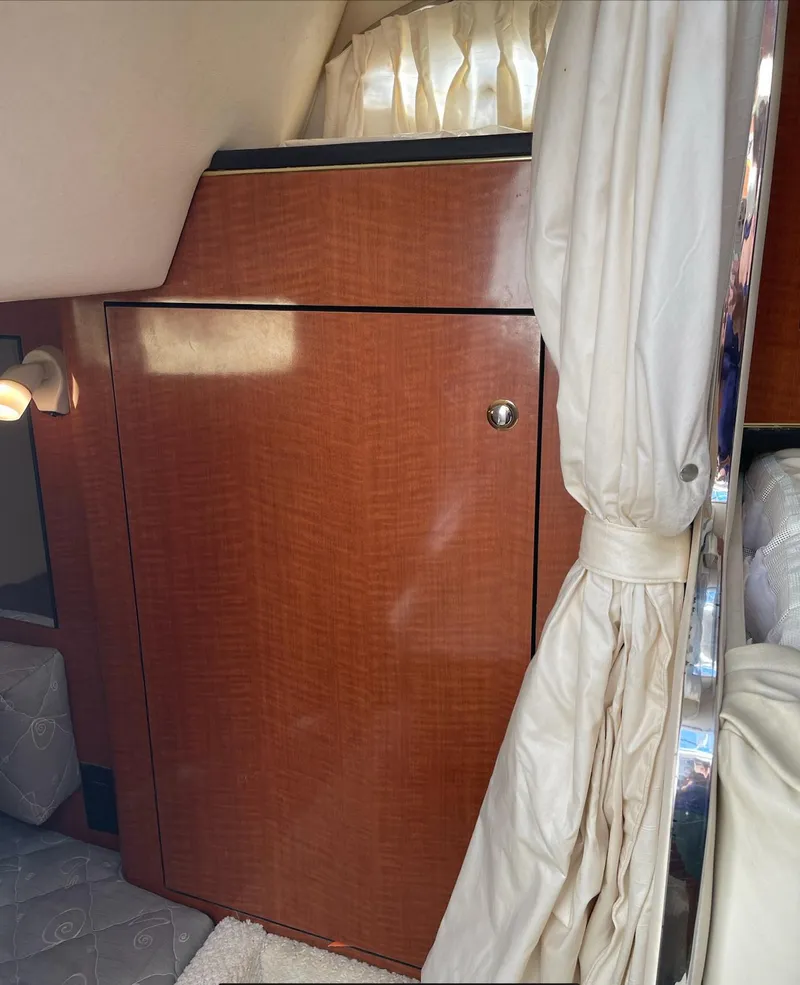 Slide: The Image of 2002 Sea Ray 280 Sundancer cabin interior with wooden cabinet and curtains. - 19
