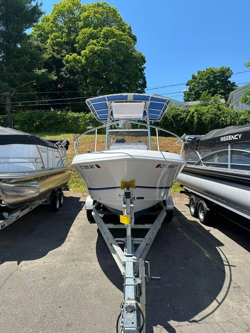 Slide: The Image of 2002 Pro-Line 20 Sport boat on trailer, parked between other boats. - 8