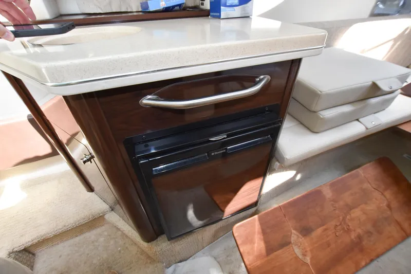 Slide: The Image of 2015 Sea Ray 260 Sundancer cabin kitchenette with mini fridge and countertop. - 15