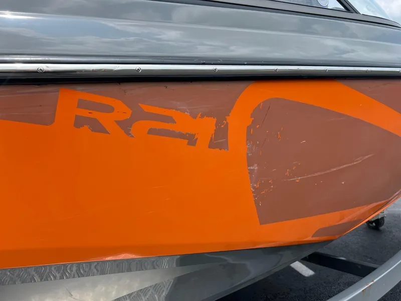 Slide: The Image of 2017 Tigé R21 boat with visible hull damage and scratched orange paint. - 17