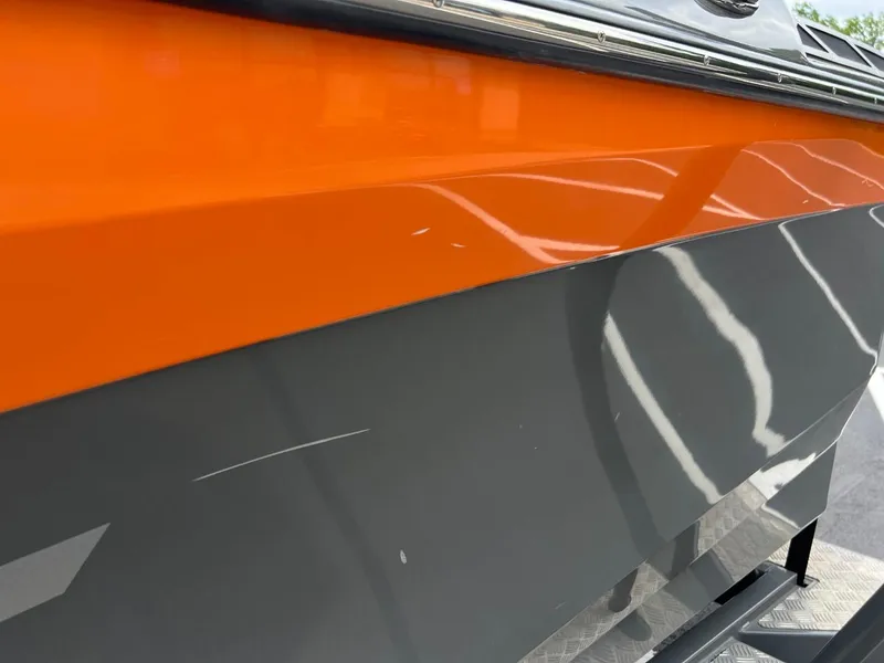 Slide: The Image of Close-up of a 2017 Tigé R21 boat with orange and gray hull. - 21