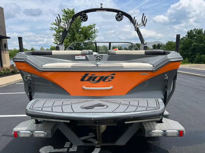 Slide: The Image of 2017 Tigé R21 boat, rear view, orange and gray, parked on asphalt. - 4