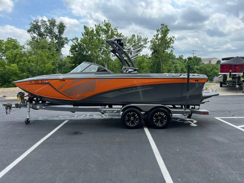 Slide: The Image of 2017 Tigé R21 boat on a trailer, orange and gray, parked outdoors. - 6