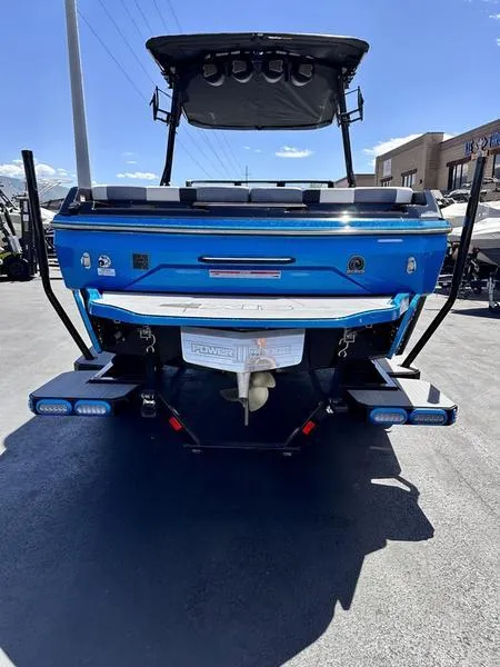 Slide: The Image of 2024 Axis A225 boat, rear view, blue color, parked outdoors under clear sky. - 7