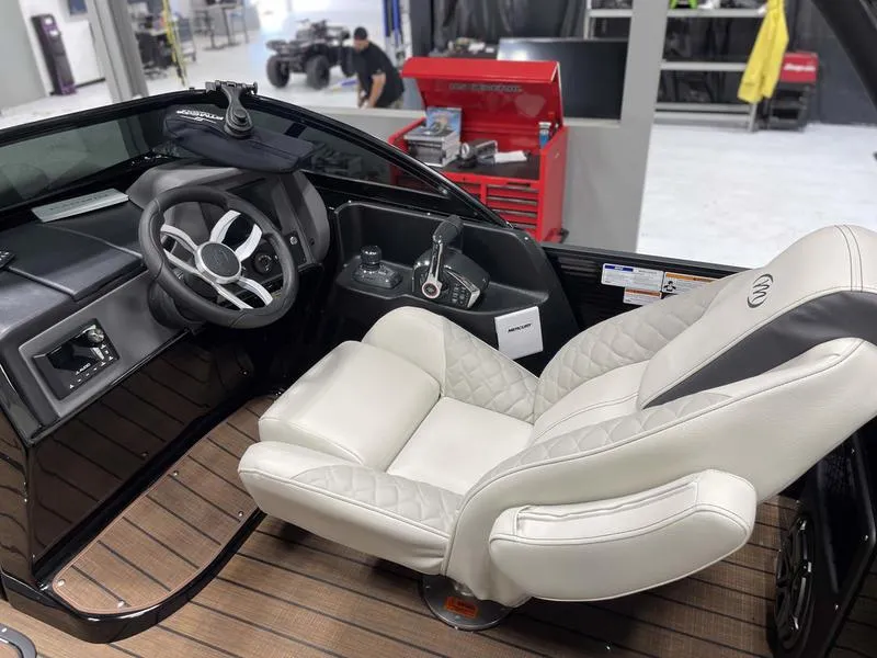 Slide: The Image of 2024 Manitou 25 LX SRW Dual Engine boat cockpit with luxurious captain's chair and modern controls. - 6