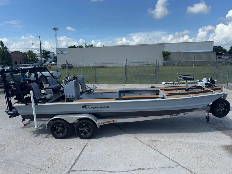 Slide: The Image of 2023 Pro-Drive 22x72 SBX boat on trailer, parked outdoors under a blue sky. - 11