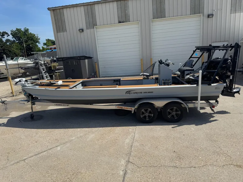 Slide: The Image of 2023 Pro-Drive 22x72 SBX boat on trailer, parked outside a warehouse. - 15