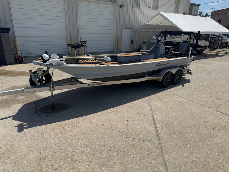 Slide: The Image of 2023 Pro-Drive 22x72 SBX boat on trailer, parked outside a building. - 16