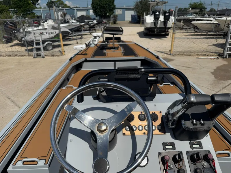 Slide: The Image of 2023 Pro-Drive 22x72 SBX boat dashboard with steering wheel and controls in a marina setting. - 32