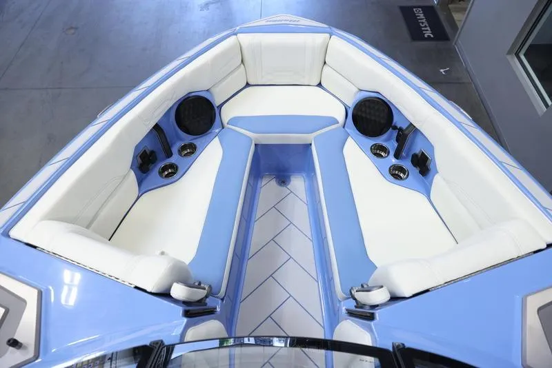Slide: The Image of 2024 Malibu 26 LSV boat interior with white and blue seating, cup holders, and speakers. - 22
