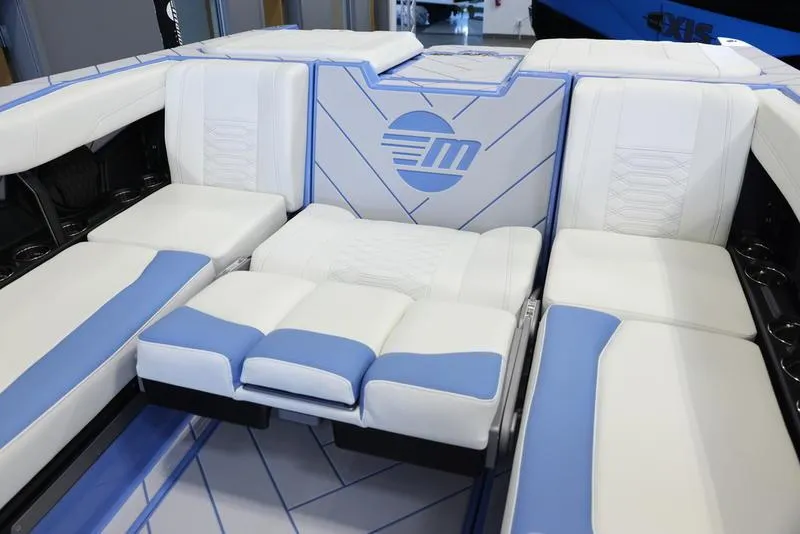 Slide: The Image of 2024 Malibu 26 LSV boat interior with white and blue cushioned seating. - 27