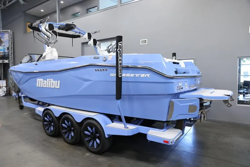 Slide: The Image of 2024 Malibu 26 LSV boat in showroom, blue exterior, on a trailer. - 4