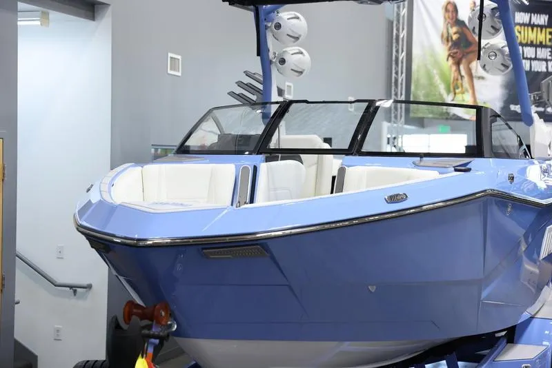 Slide: The Image of 2024 Malibu 26 LSV boat in showroom, front view, blue exterior, white interior. - 9