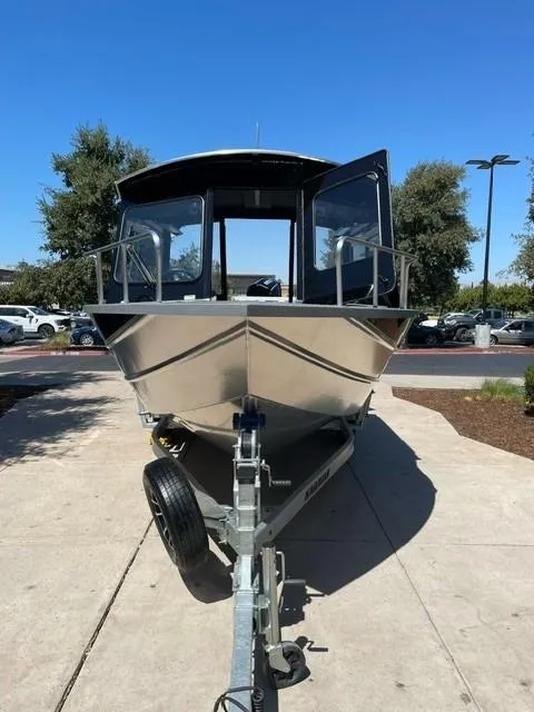 Slide: The Image of 2024 Spartan 220 Maximus boat on trailer, parked outdoors under clear blue sky. - 2