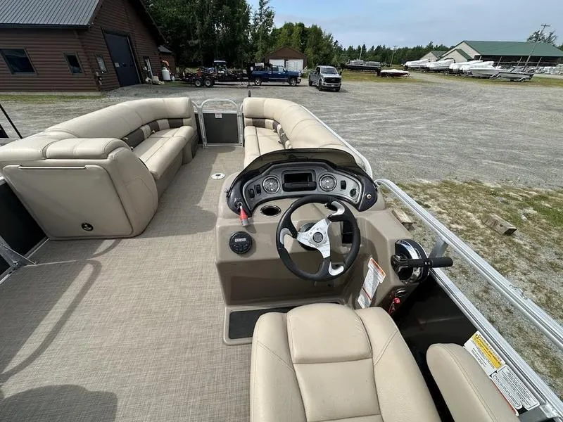 Slide: The Image of 2021 Sun Tracker PB 24 DLX pontoon boat interior with beige seating and steering console. - 3