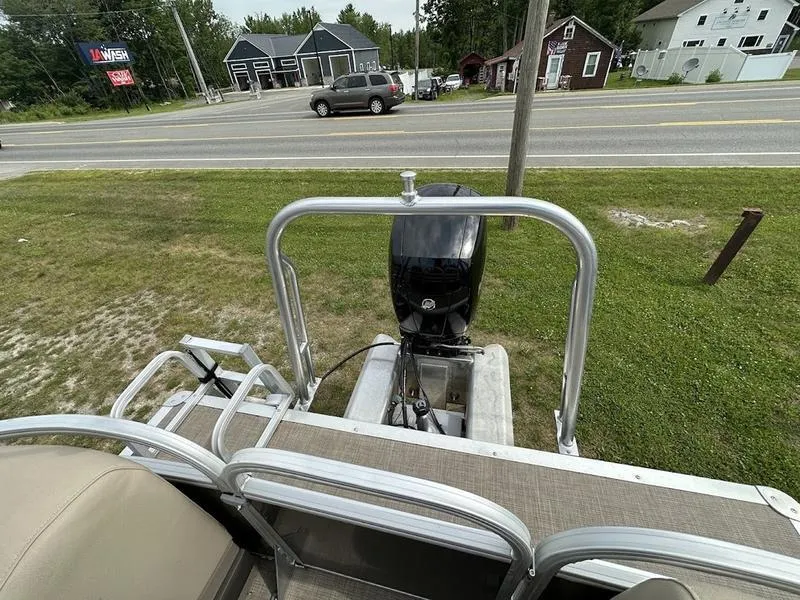 Slide: The Image of 2021 Sun Tracker PB 24 DLX pontoon boat with outboard motor, parked near a road. - 7