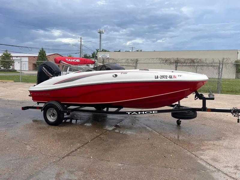 The Image of 2020 Tahoe T16 red and white boat on trailer in parking lot. - 1