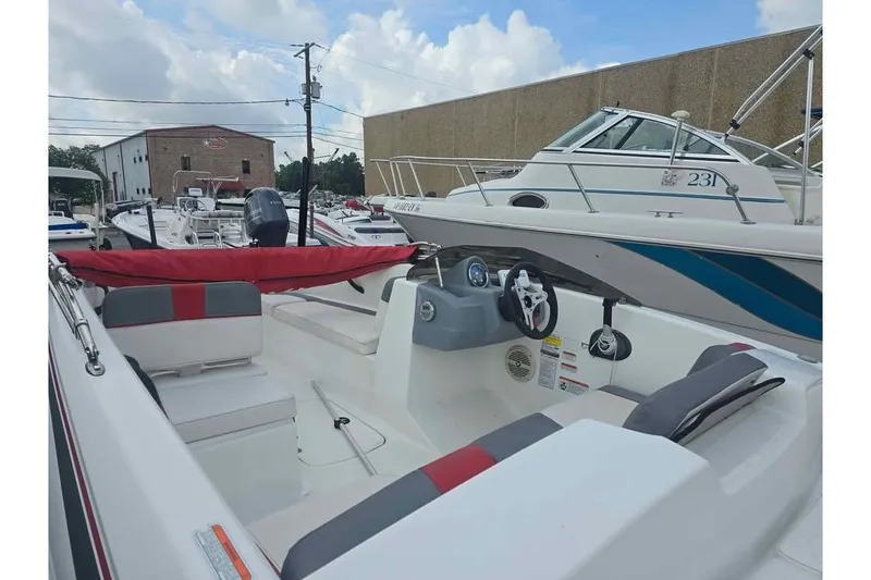 Slide: The Image of 2020 Tahoe T16 boat interior with steering wheel and seating, parked in a marina. - 3