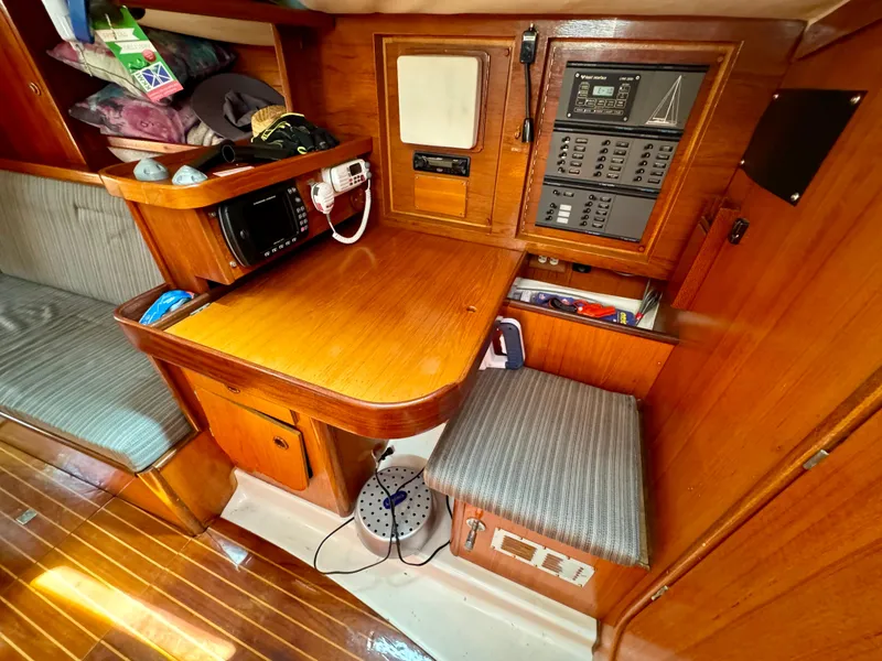 Slide: The Image of Interior of 1988 Beneteau First Class 12 sailboat, featuring wooden cabinetry and a cushioned bench. - 14