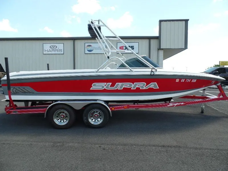 Slide: The Image of 2003 Supra 21 boat with red and white design on trailer. - 1