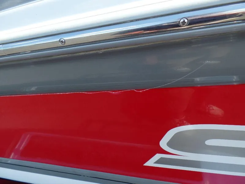 Slide: The Image of Close-up of a 2003 Supra 21 boat with a visible scratch on the red hull. - 17