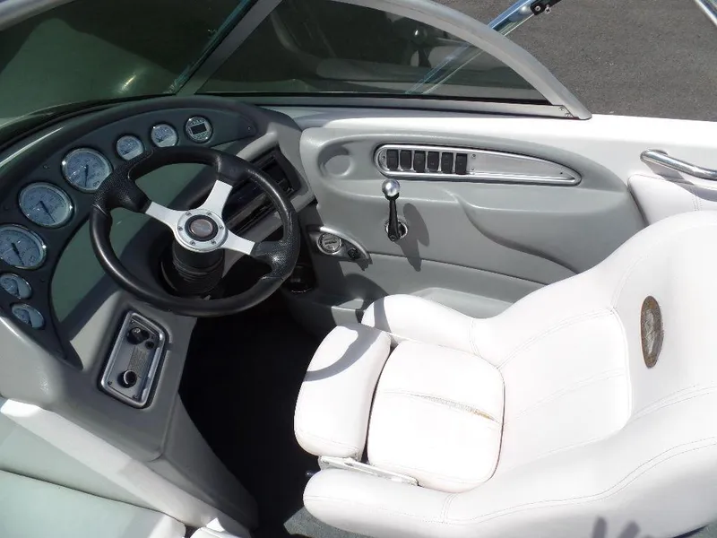 Slide: The Image of Interior of a 2003 Supra 21 boat with steering wheel and white captain's seat. - 8