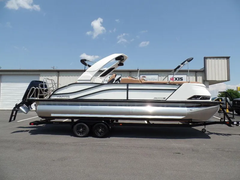 Slide: The Image of 2025 Harris Grand Mariner 250 pontoon boat on trailer, parked outdoors. - 0