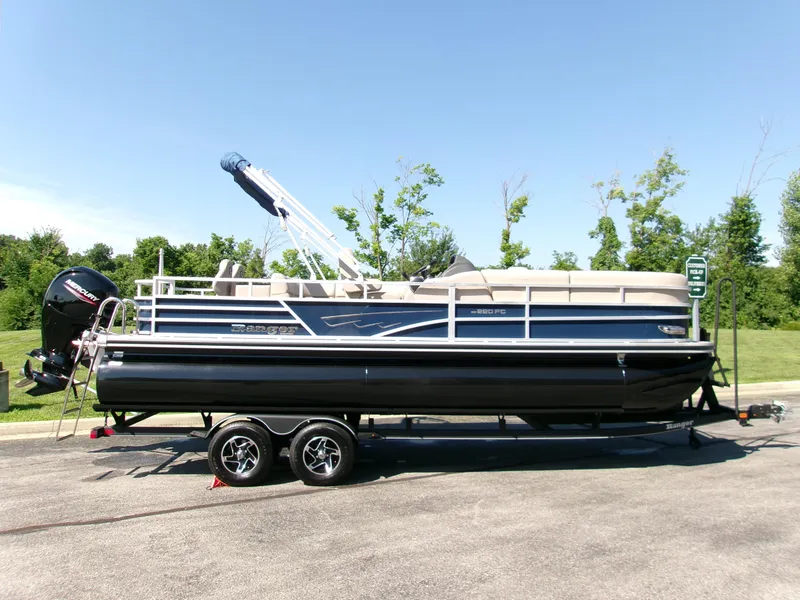 The Image of 2024 Ranger Reata 220FC pontoon boat on trailer, parked outdoors on a sunny day. - 0