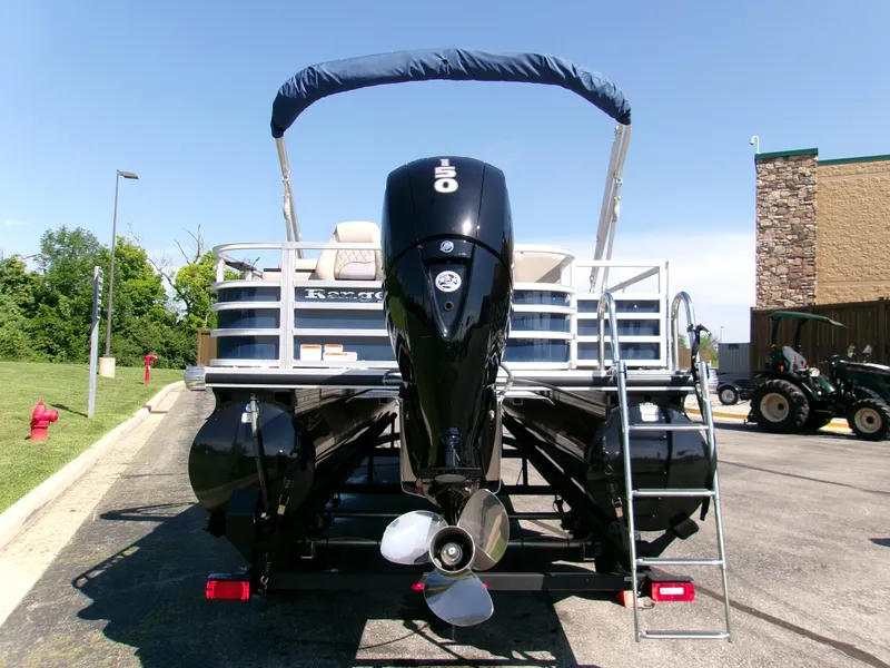 Slide: The Image of 2024 Ranger Reata 220FC pontoon boat with outboard motor and ladder, parked outdoors. - 2