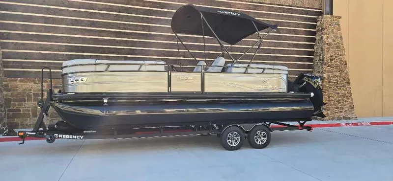 Slide: The Image of 2024 Regency 230 DL3 pontoon boat on trailer, parked outdoors. - 0