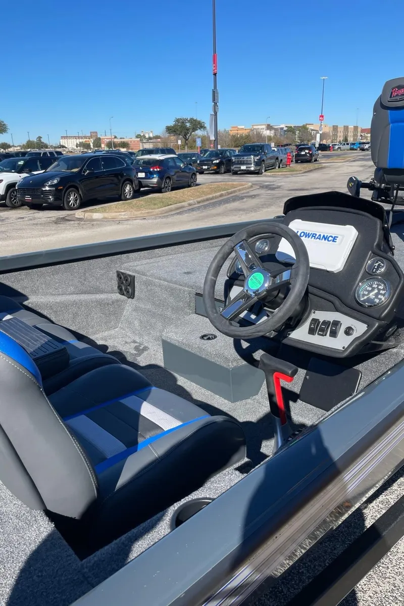 Slide: The Image of 2024 Ranger RT198P boat interior with steering wheel and seating, parked outdoors. - 2