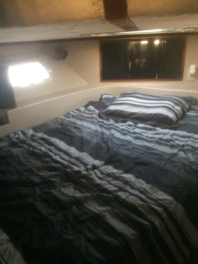 Slide: The Image of 1985 Bluewater 42 Coastal Cruiser cabin with striped bedding and window view. - 11