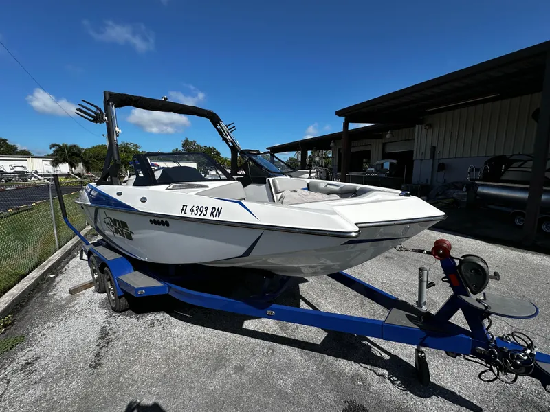 Slide: The Image of 2018 Axis A20 boat on trailer, parked outdoors under clear blue sky. - 16