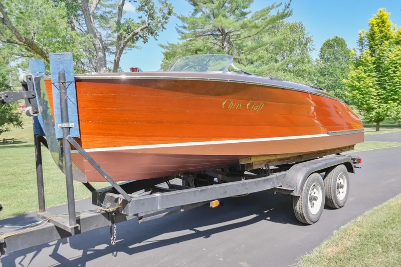 Slide: The Image of 1942 Chris-Craft 17 wooden boat on a trailer in a park setting. - 1