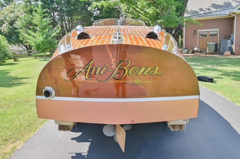 Slide: The Image of 1942 Chris-Craft 17 boat with Ani-Bons name on the stern, parked on a driveway. - 4