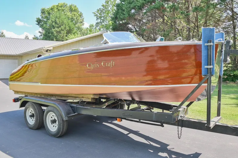 The Image of 1942 Chris-Craft 17 wooden boat on a trailer in a driveway. - 0