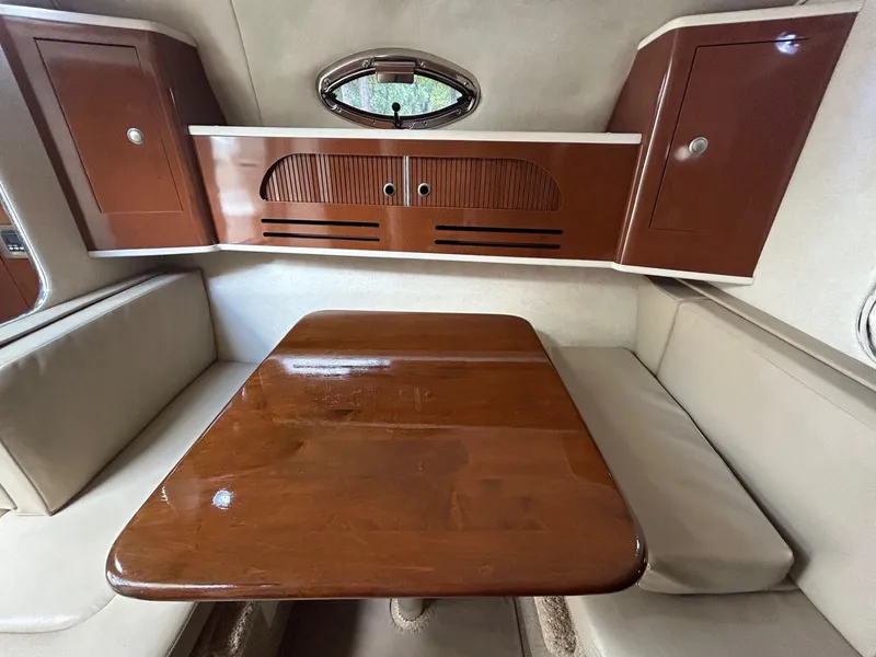 Slide: The Image of 2008 Sea Ray 280DA cabin interior with wooden table and cushioned seating. - 13