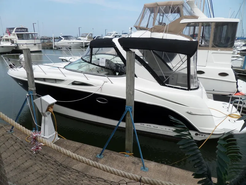 The Image of 2008 Bayliner 320 Express docked at marina, featuring sleek black and white design. - 0