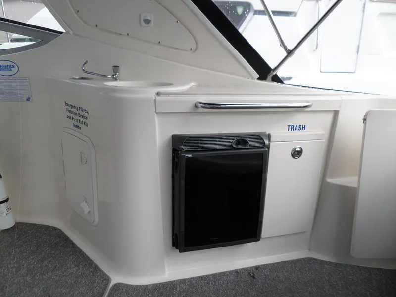 Slide: The Image of 2008 Bayliner 320 Express boat interior with sink, trash compartment, and mini fridge. - 26