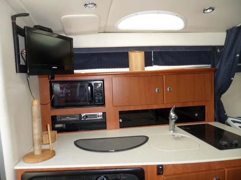 Slide: The Image of 2008 Bayliner 320 Express yacht kitchen with TV, microwave, and stove. - 32