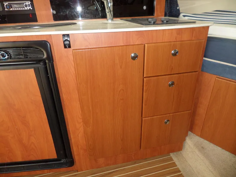 Slide: The Image of 2008 Bayliner 320 Express kitchen area with wooden cabinets and mini fridge. - 33