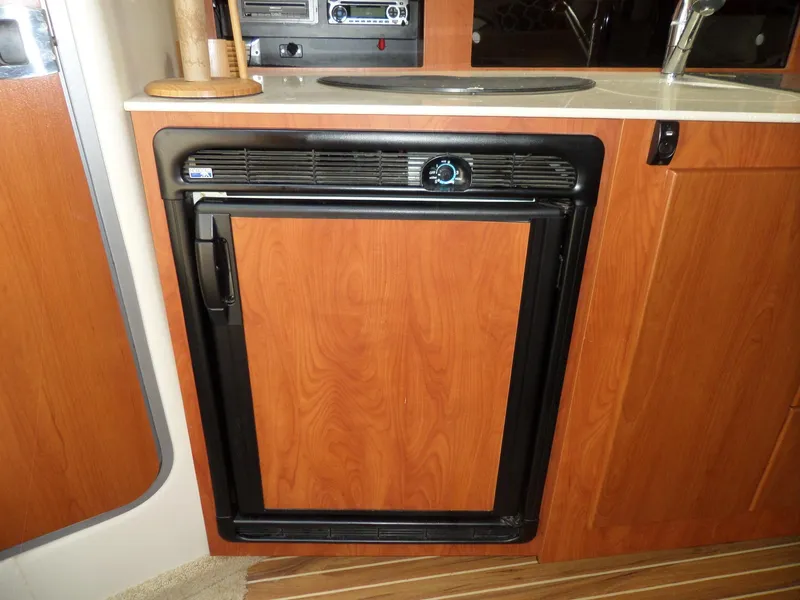 Slide: The Image of 2008 Bayliner 320 Express galley with built-in refrigerator and wooden cabinetry. - 34