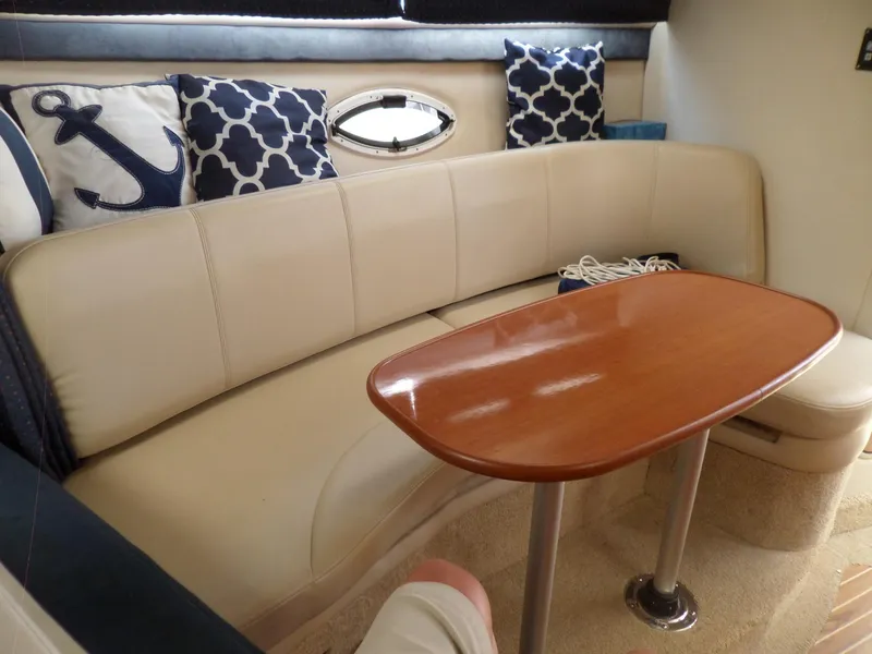 Slide: The Image of Interior seating area of 2008 Bayliner 320 Express with beige leather and nautical-themed pillows. - 39