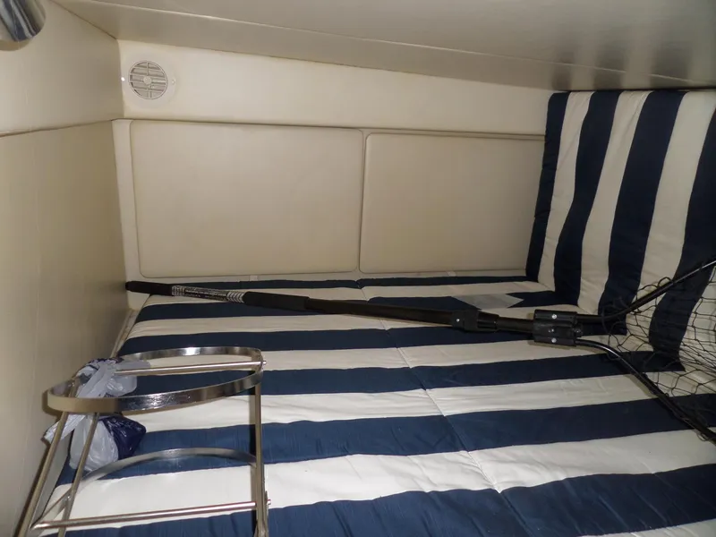 Slide: The Image of Interior cabin of 2008 Bayliner 320 Express with striped bedding and fishing gear. - 48