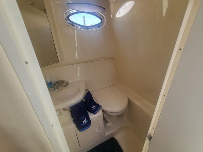 Slide: The Image of 1999 Sea Ray 290 Sundancer bathroom with sink, toilet, and porthole window. - 10